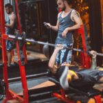 Fitness Apps - Sporty fitness trainer and man lifting barbell