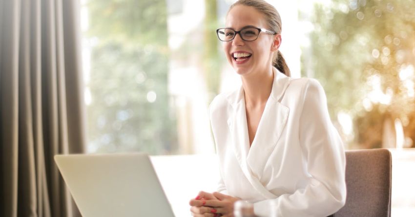 Family Projects - Laughing businesswoman working in office with laptop