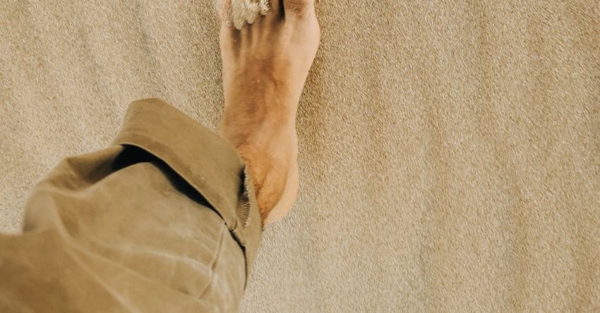 Travel Destinations - From above of crop anonymous barefooted male traveler walking on sandy terrain in desert